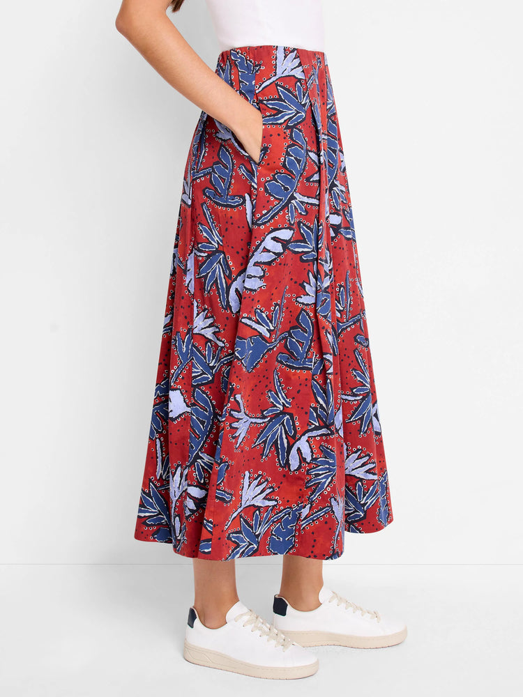 Red midi skirt with blue and purple leaf print, pleated, and side pockets.