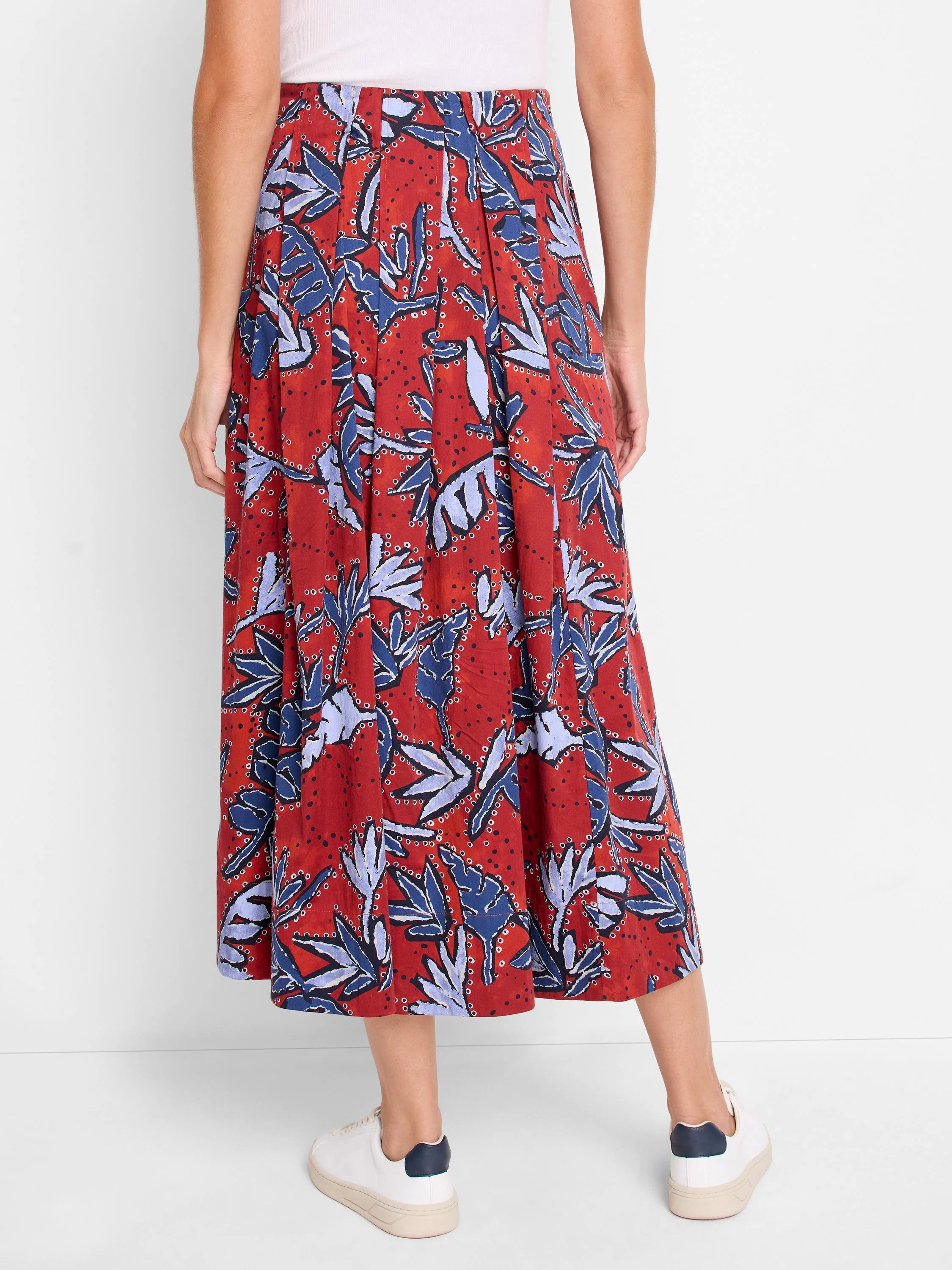 Red midi skirt with pleated design. Features a blue and purple leaf print on a rust-colored background.