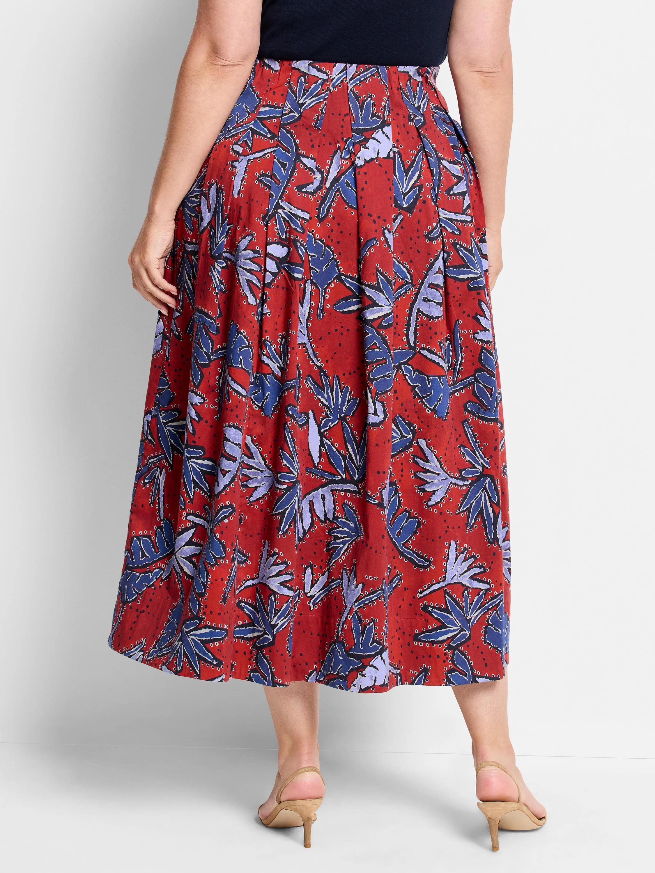 Red midi skirt with pleated detail. Features a blue and purple leaf print on a red background.
