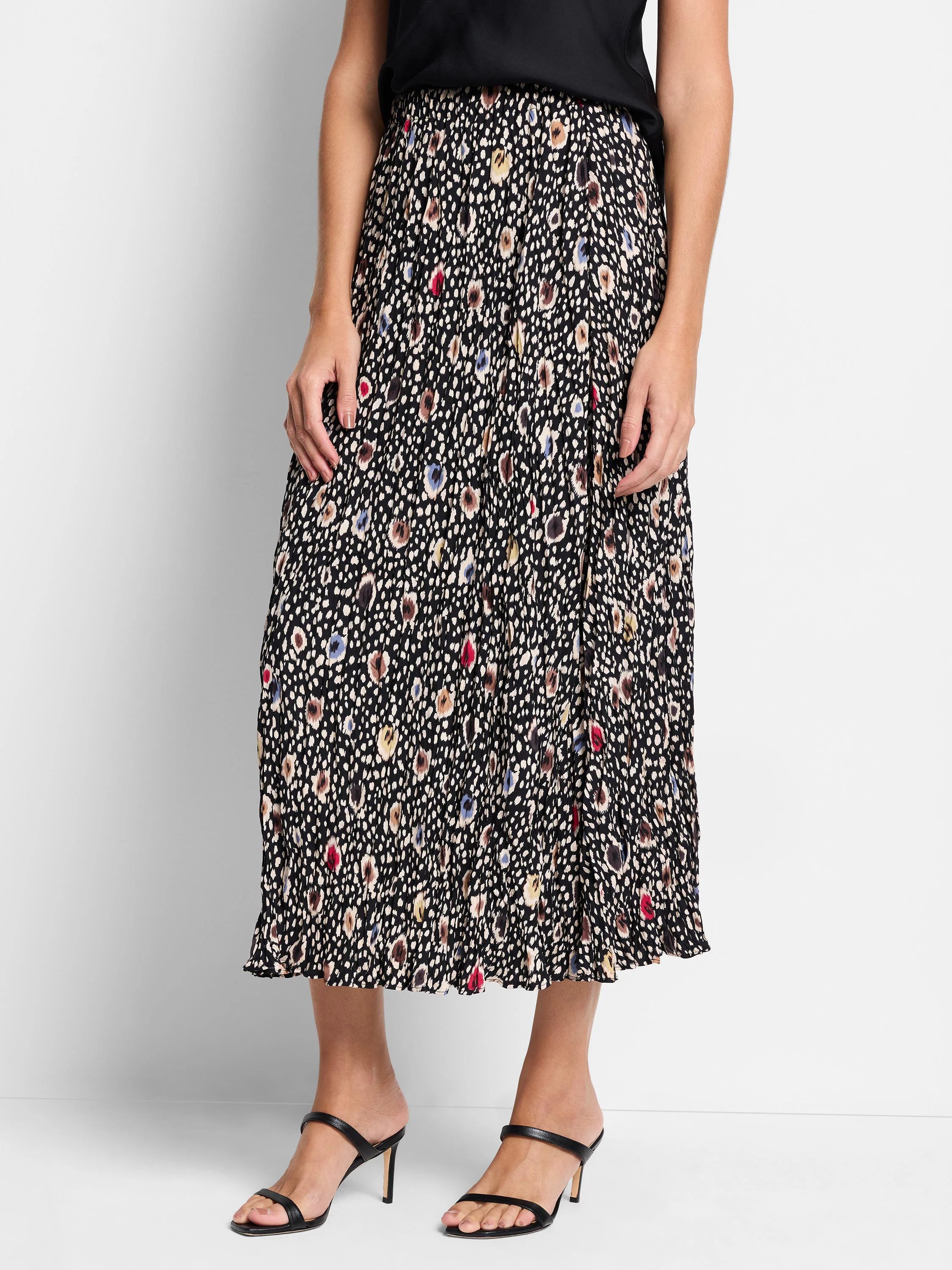 Black pleated midi skirt with multicolored spotted pattern. Beige, brown, red, and blue spots on black background.
