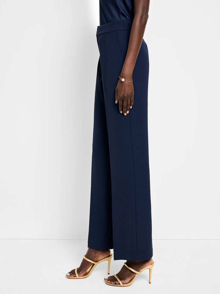 Navy blue wide-leg trousers shown on a model. The pants have a center crease and side pockets. The model is wearing...