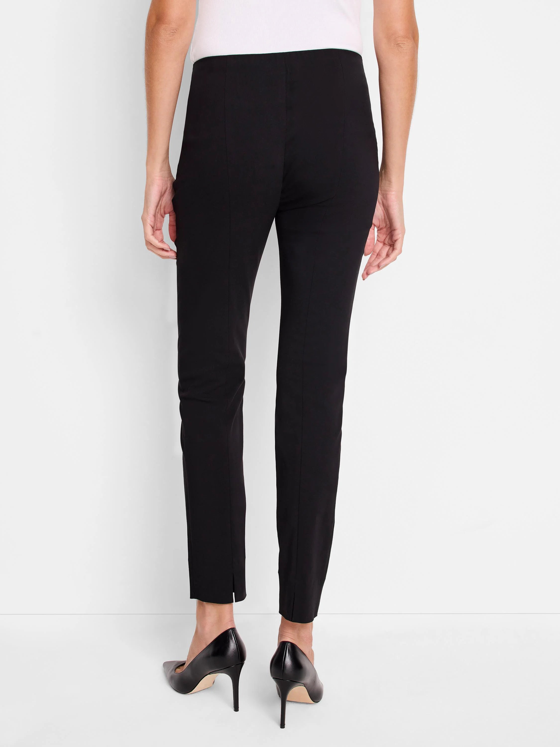 Black pull-on pants, slim fit, ankle length, side slits. Rear view.