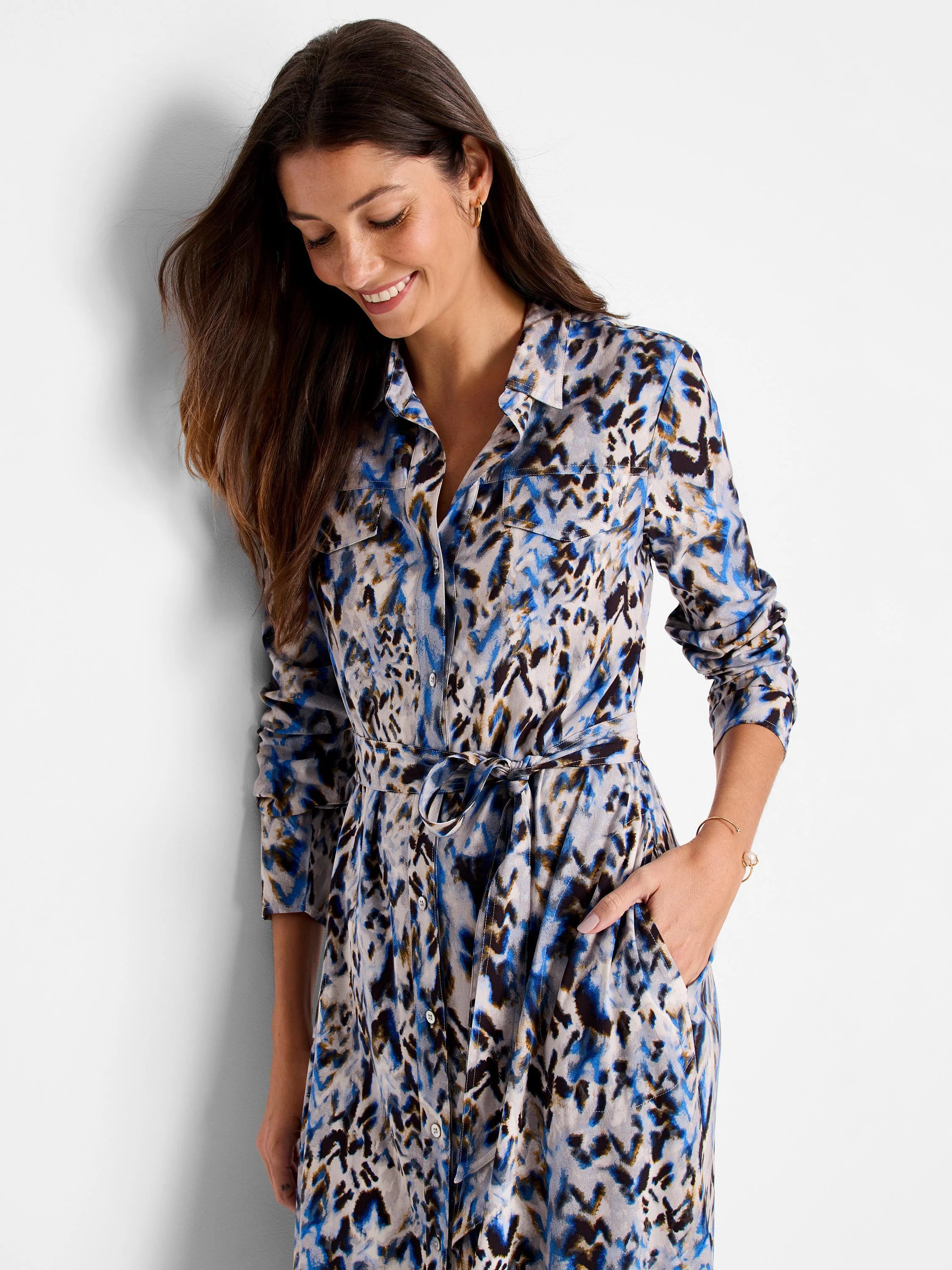 Long-sleeved shirt dress with belted waist. Blue, brown, and beige chevron print. Features front pockets.