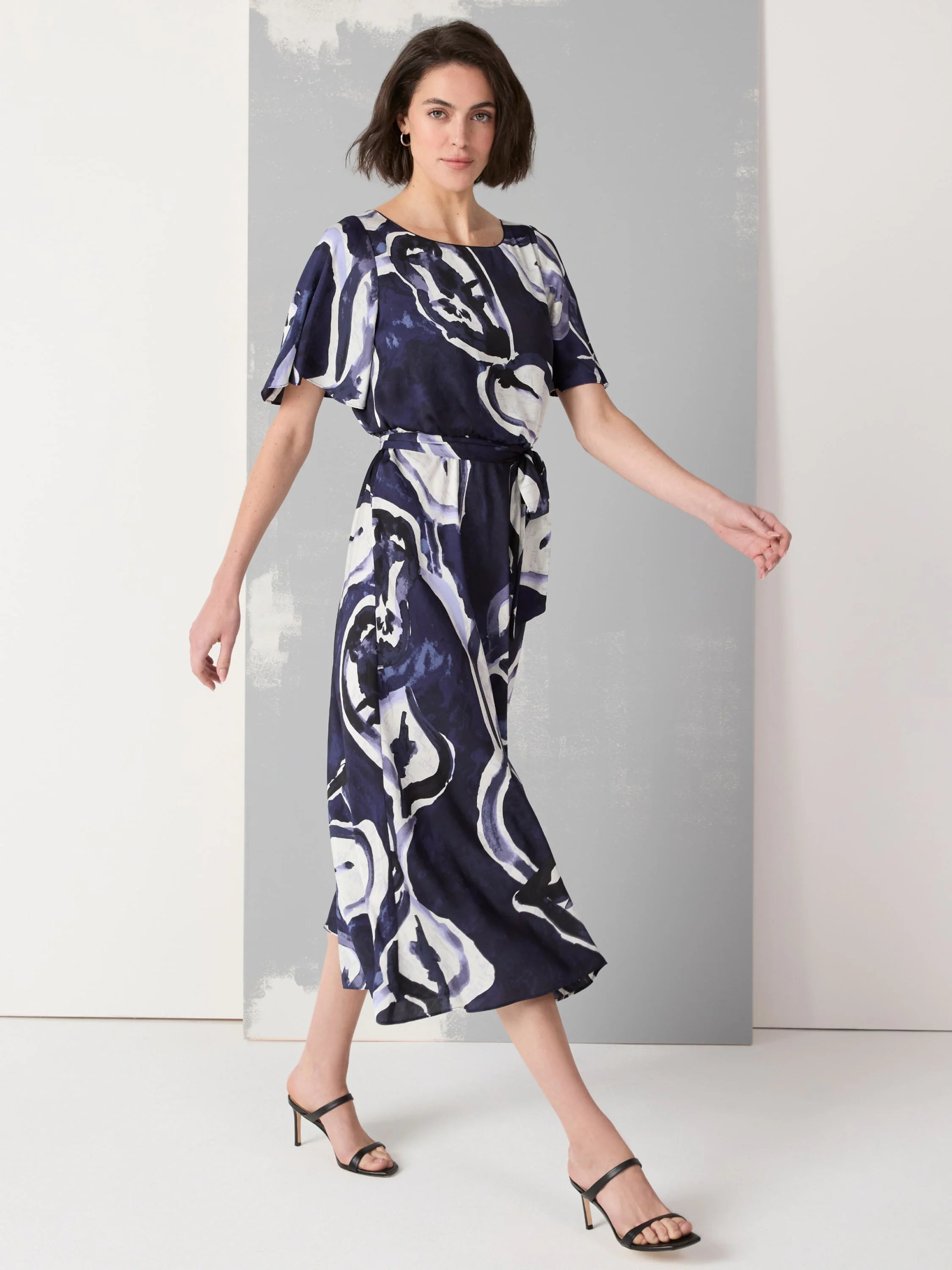 Midi dress with short flutter sleeves. Navy, white, and light purple abstract watercolor print. Belted waist.