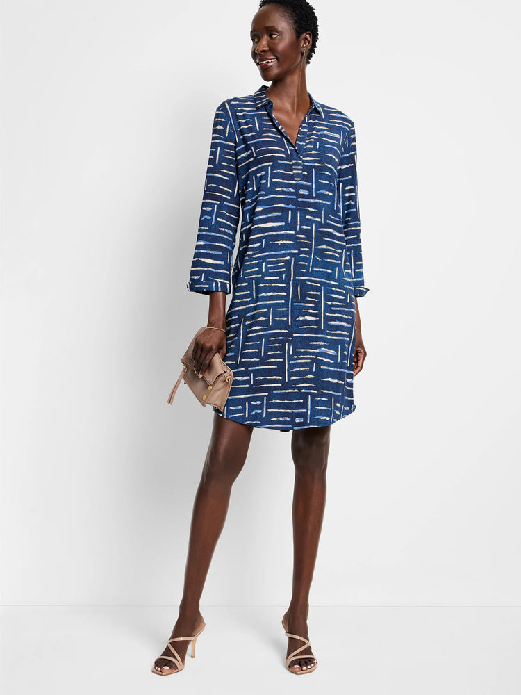 Indigo blue shirt dress with a white and light blue geometric pattern. Three-quarter sleeves, collared neckline.