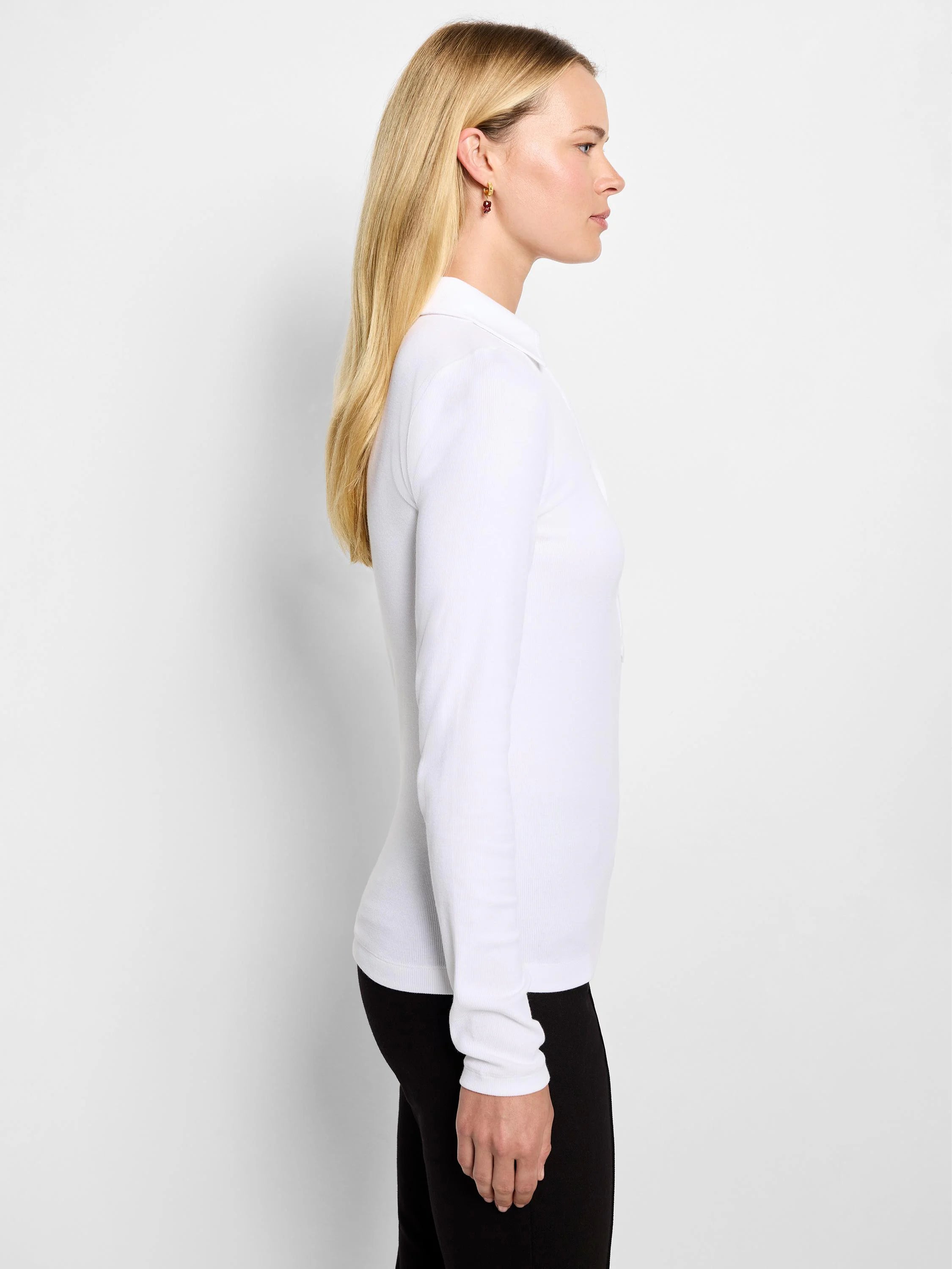 White long sleeve ribbed knit polo shirt with a collar, worn by a model in profile.