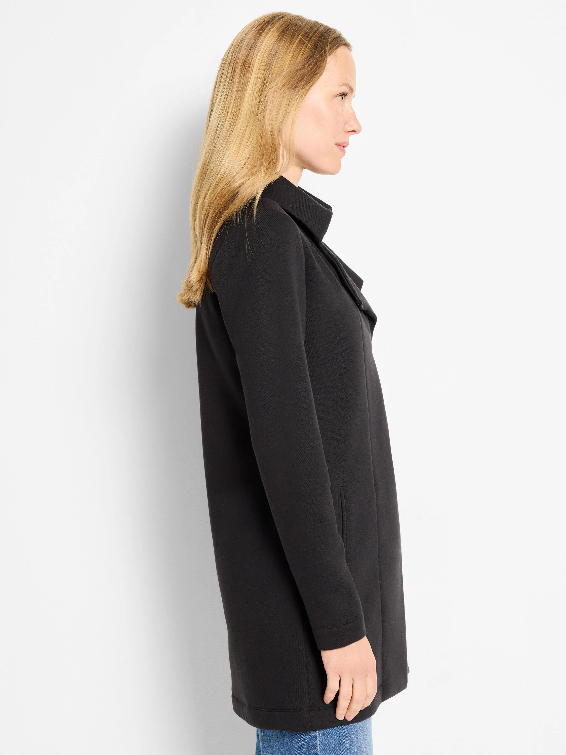 Black, mid-thigh length jacket with long sleeves, a stand-up collar, and an open, draped front.