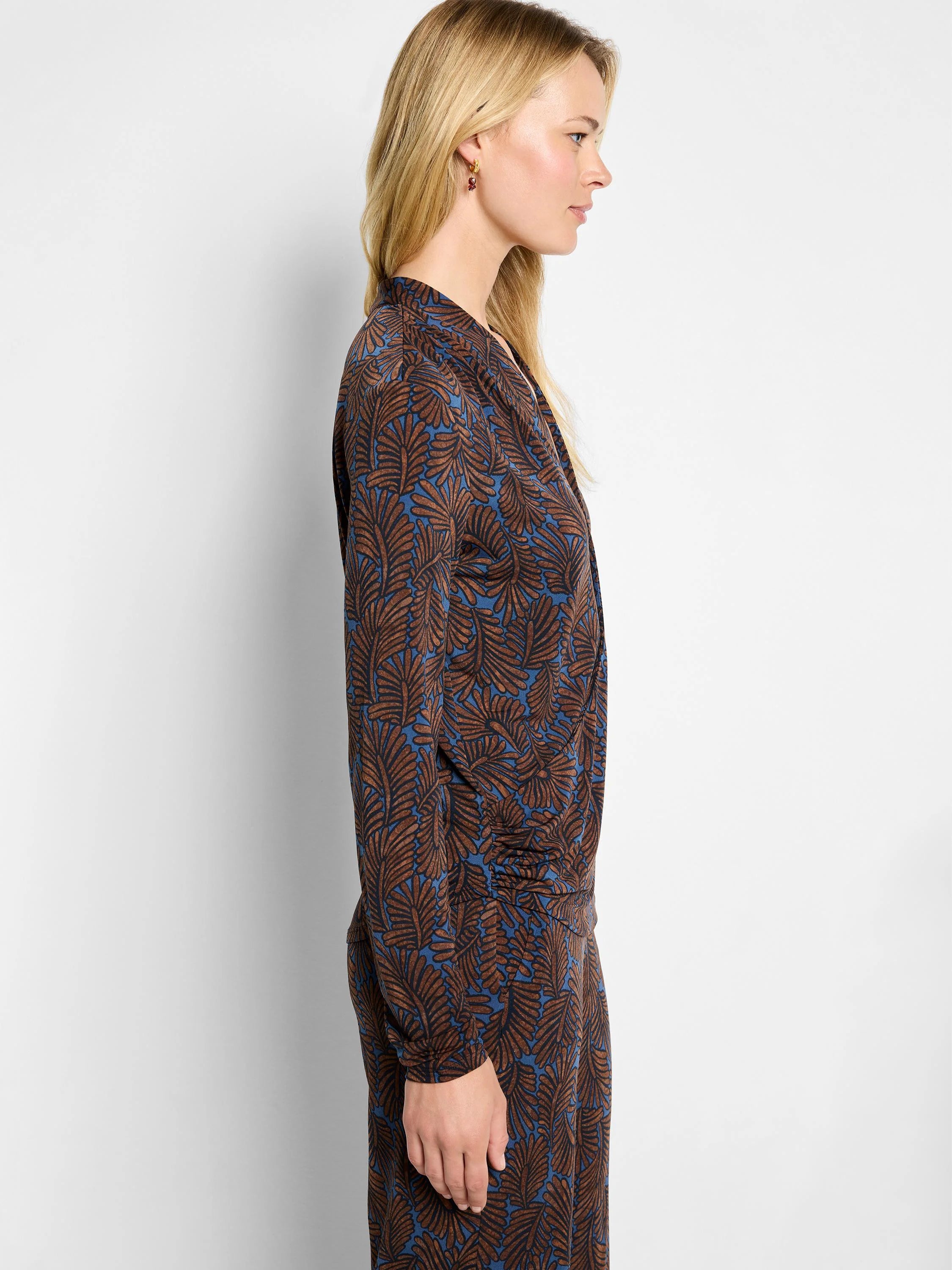 Long-sleeve wrap top with brown feather fern pattern on a blue background.