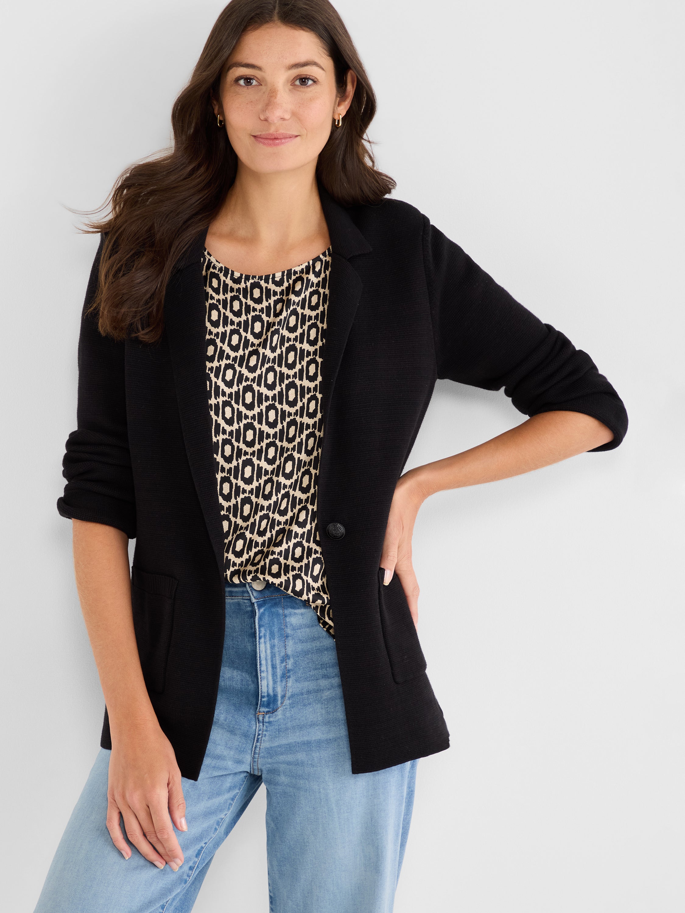 Black knit blazer with notched lapels, a single button, and pushed-up three-quarter sleeves.