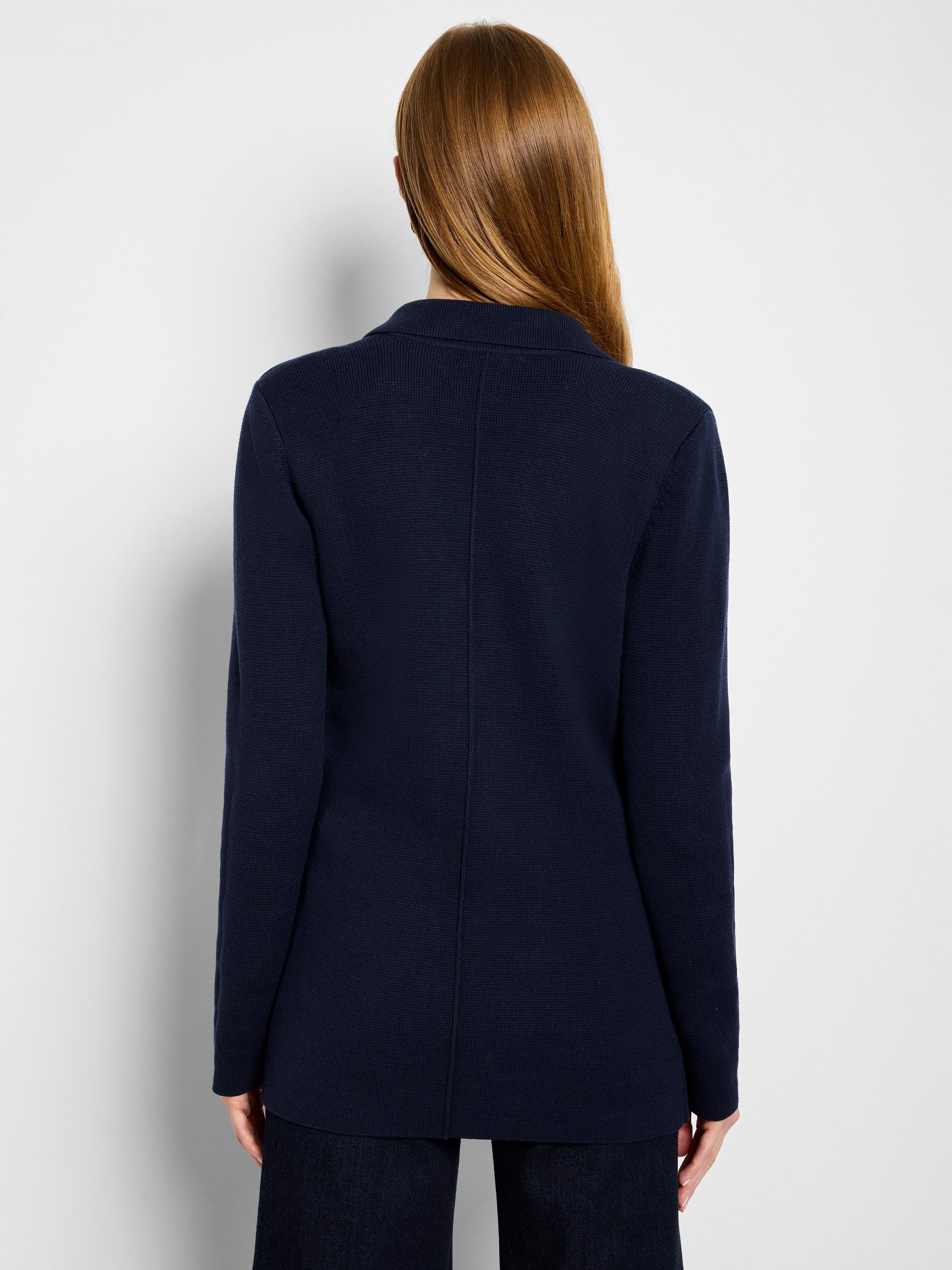Navy knit blazer, back view. Features a ribbed texture, collar, and a subtle vertical seam down the back.