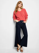 Coral V-neck sweater featuring a prominent tuck stitch texture, relaxed fit, and ribbed cuffs.