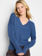 Blue V-neck sweater with a visible tuck stitch texture and ribbed cuffs.