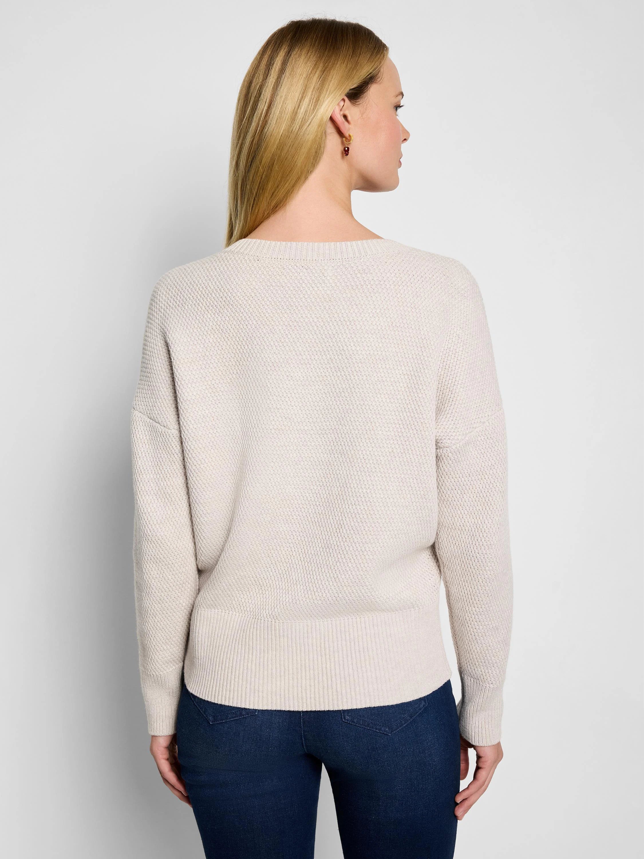 Oatmeal tuck stitch sweater, back view, with a round neck, dropped shoulders, and ribbed cuffs/hem.