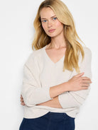 Cream V-neck sweater with visible tuck stitch texture, ribbed cuffs and hem.