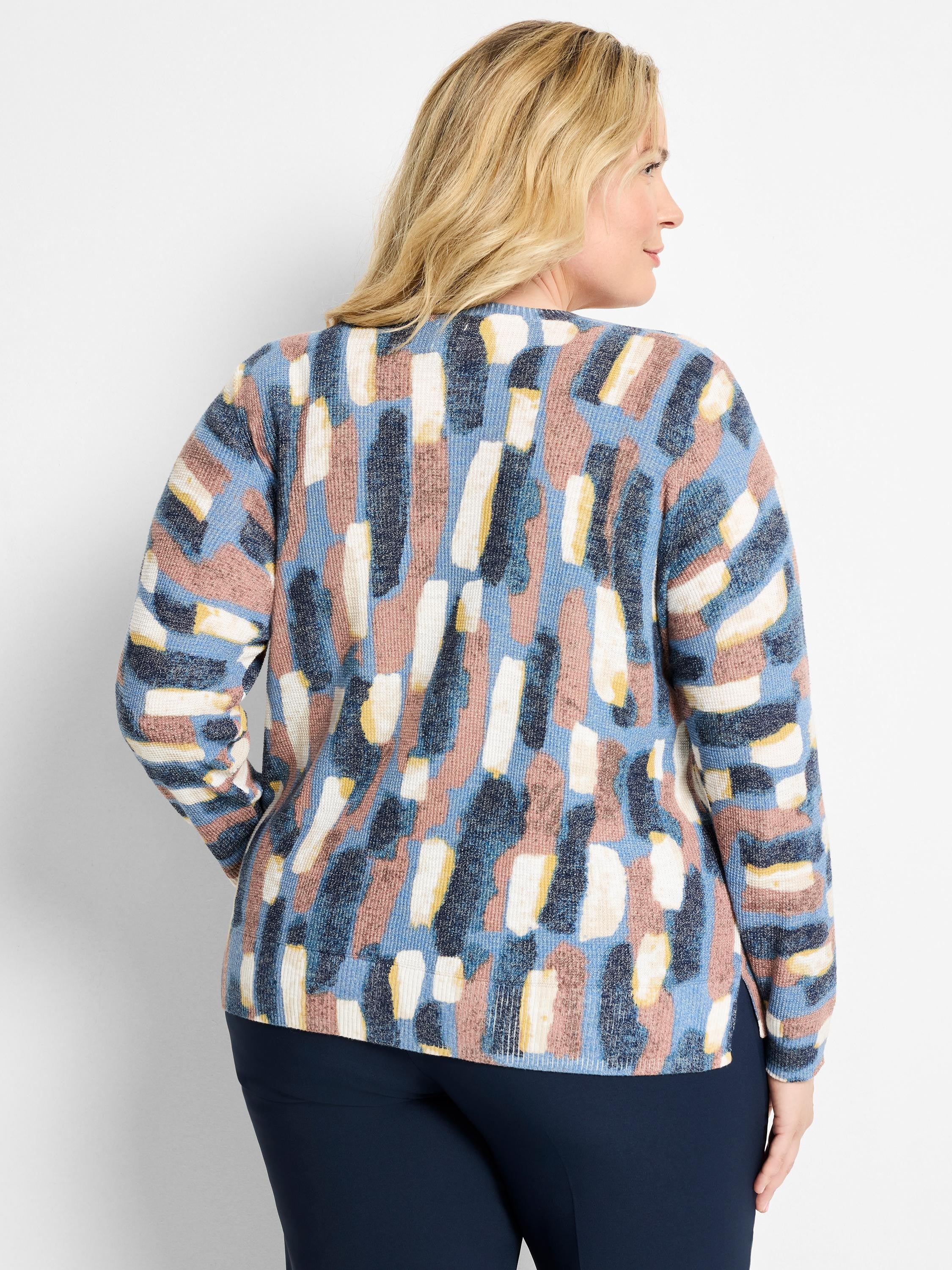 Waffle knit sweater with abstract brushstroke pattern in blues, pink, cream, and yellow. Model's back.