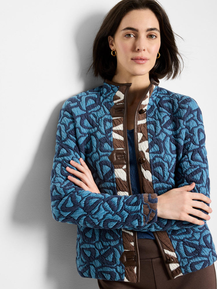 Blue quilted jacket with abstract pattern, dark brown faux leather trim & brown/white striped placket.