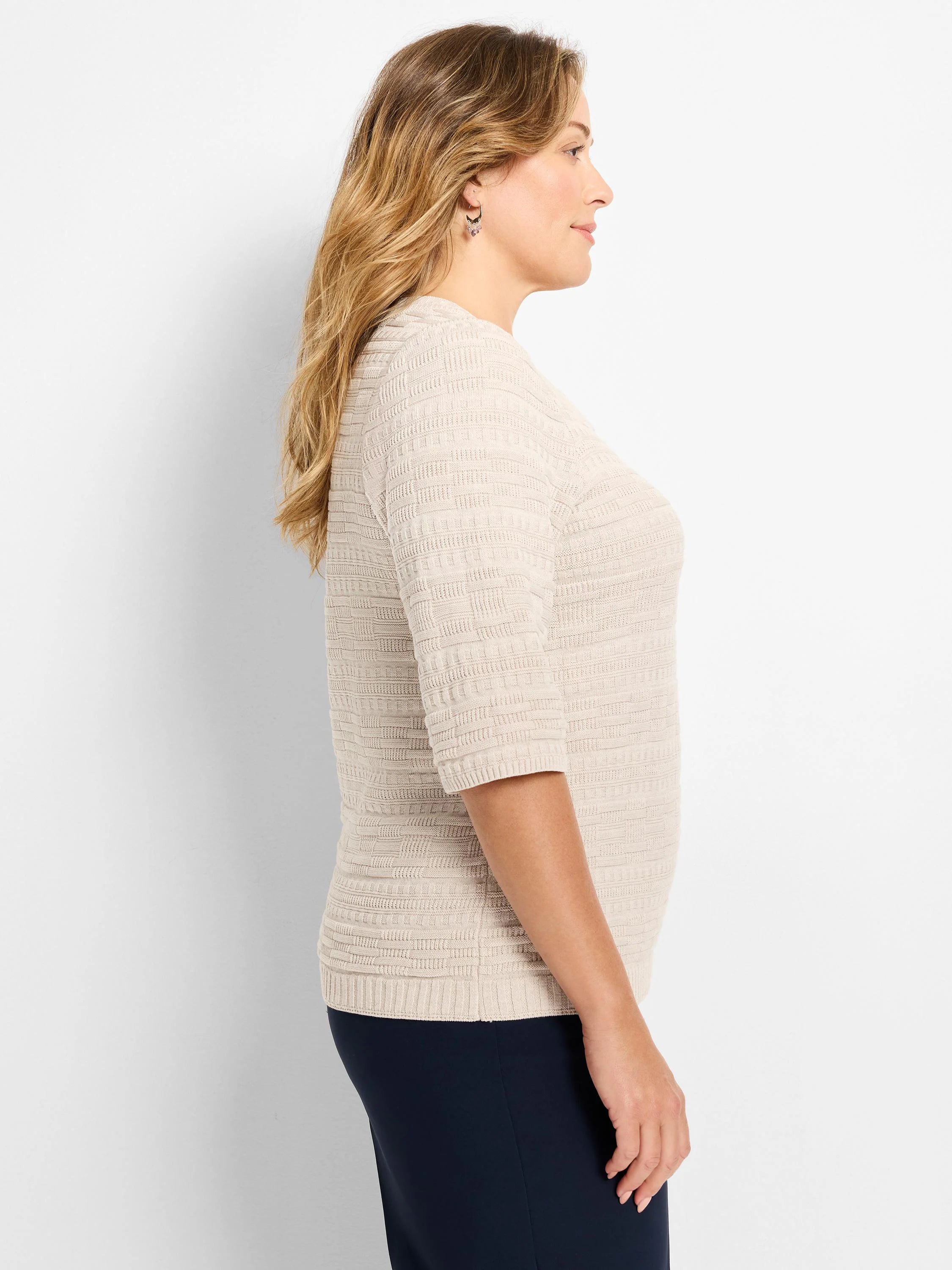 Light beige sweater tee with 3/4 sleeves. Features an all-over geometric textured knit pattern.