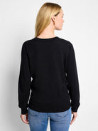 Black crew neck sweater on a model, seen from the back. Features ribbed neckband, long sleeves with cuffs, and hem.