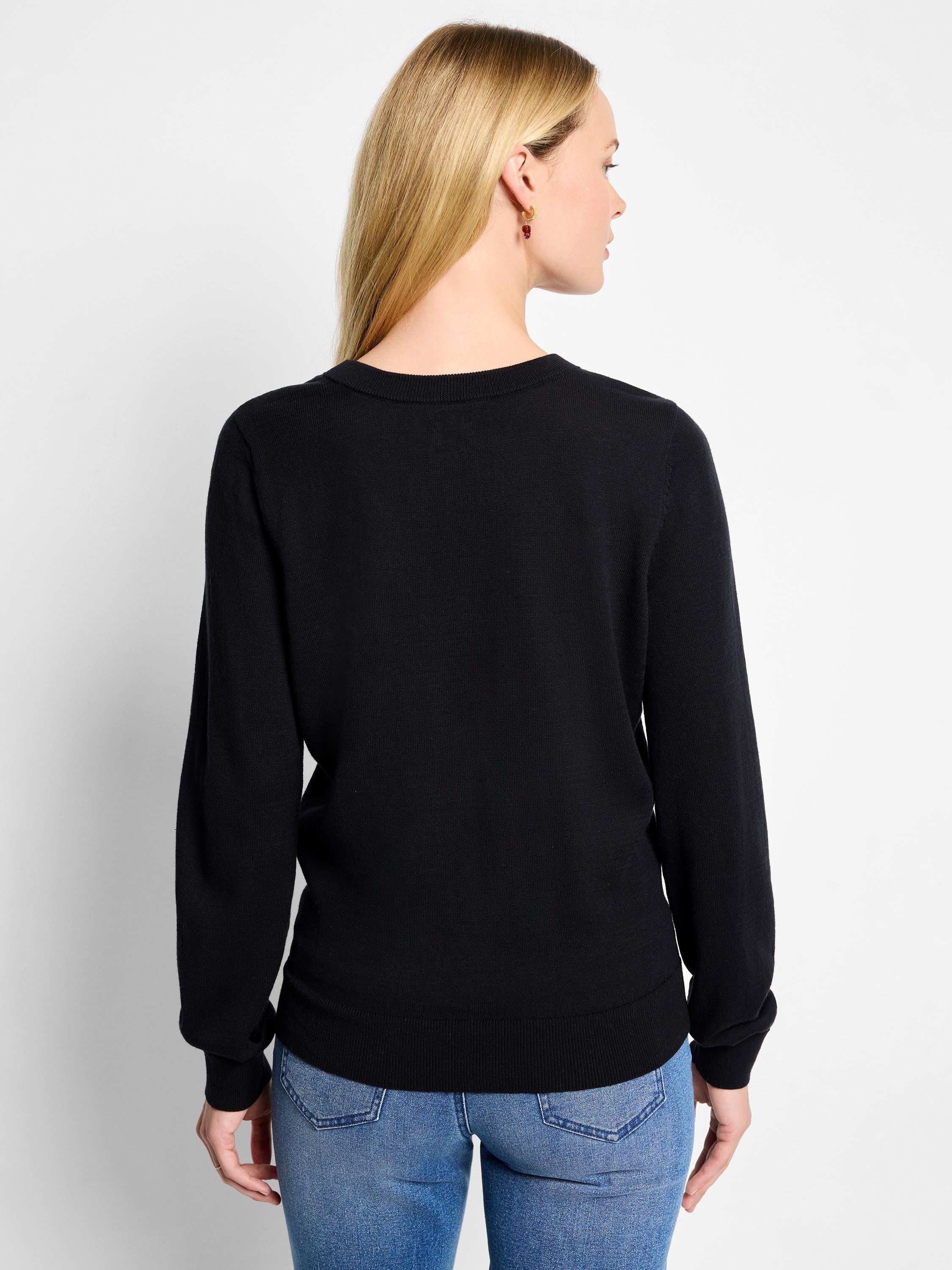 Black crew neck sweater on a model, seen from the back. Features ribbed neckband, long sleeves with cuffs, and hem.