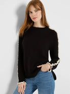 Black crew neck sweater with cream ruffles on the shoulders, down the sleeves, and at the cuffs.