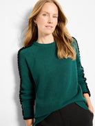 Dark green knit sweater with black ruffles running down the sleeves.
