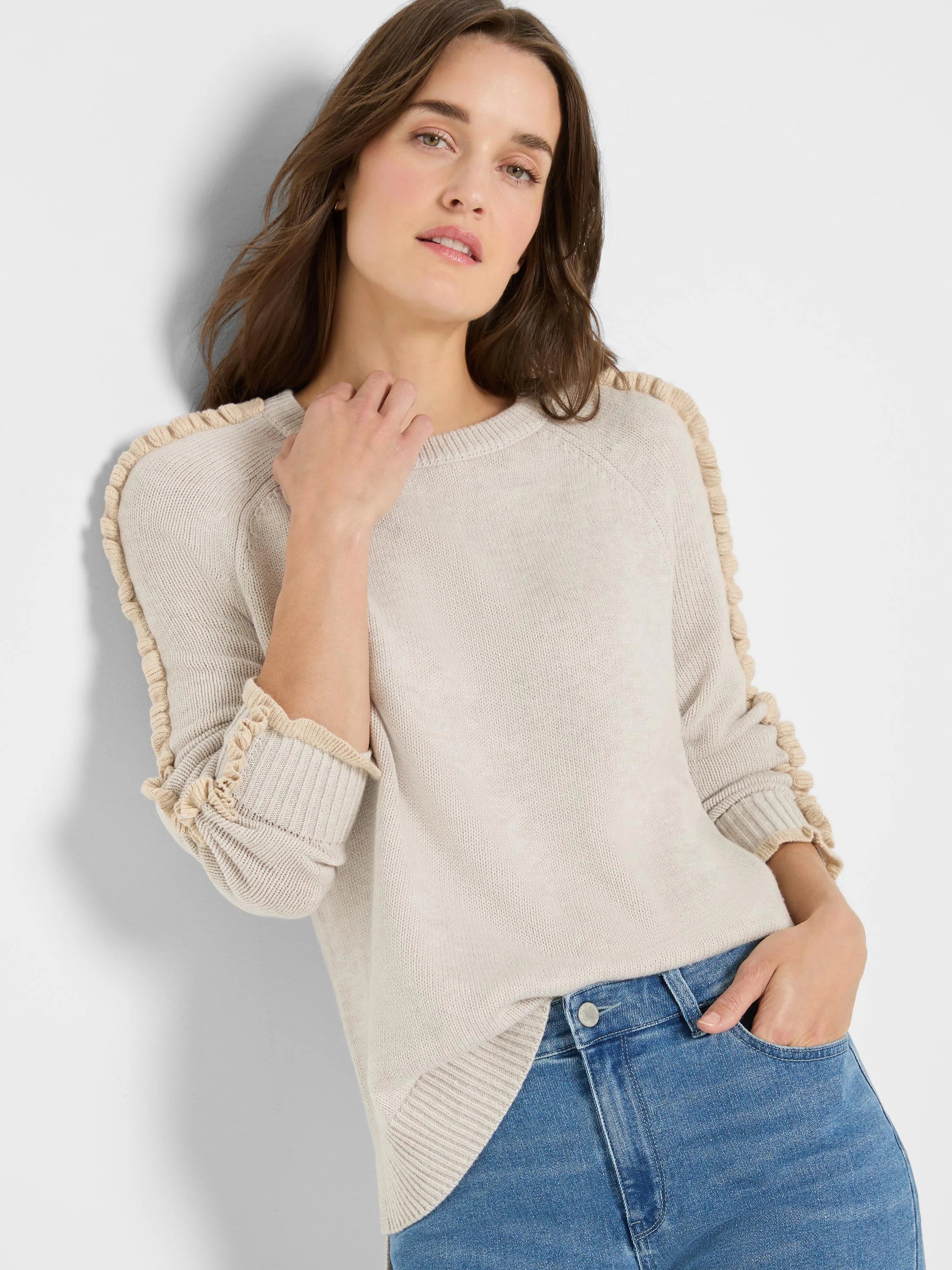 Ecru knit sweater with ruffled raglan seams and ruffled cuffs.