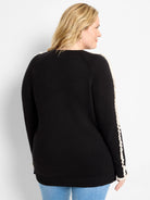 Black sweater with cream vertical ruffles on the outer sleeves and ribbed hem.