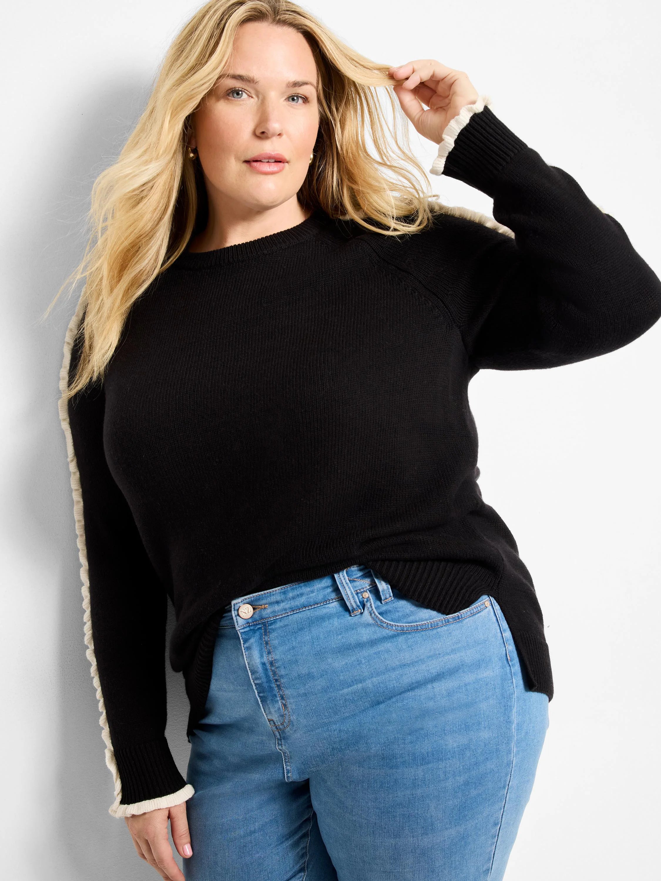 Black sweater with cream ruffles along the raglan sleeves and ribbed cuffs.