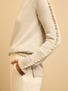 Oatmeal knit sweater with ruffles running down the sleeves and ribbed cuffs.