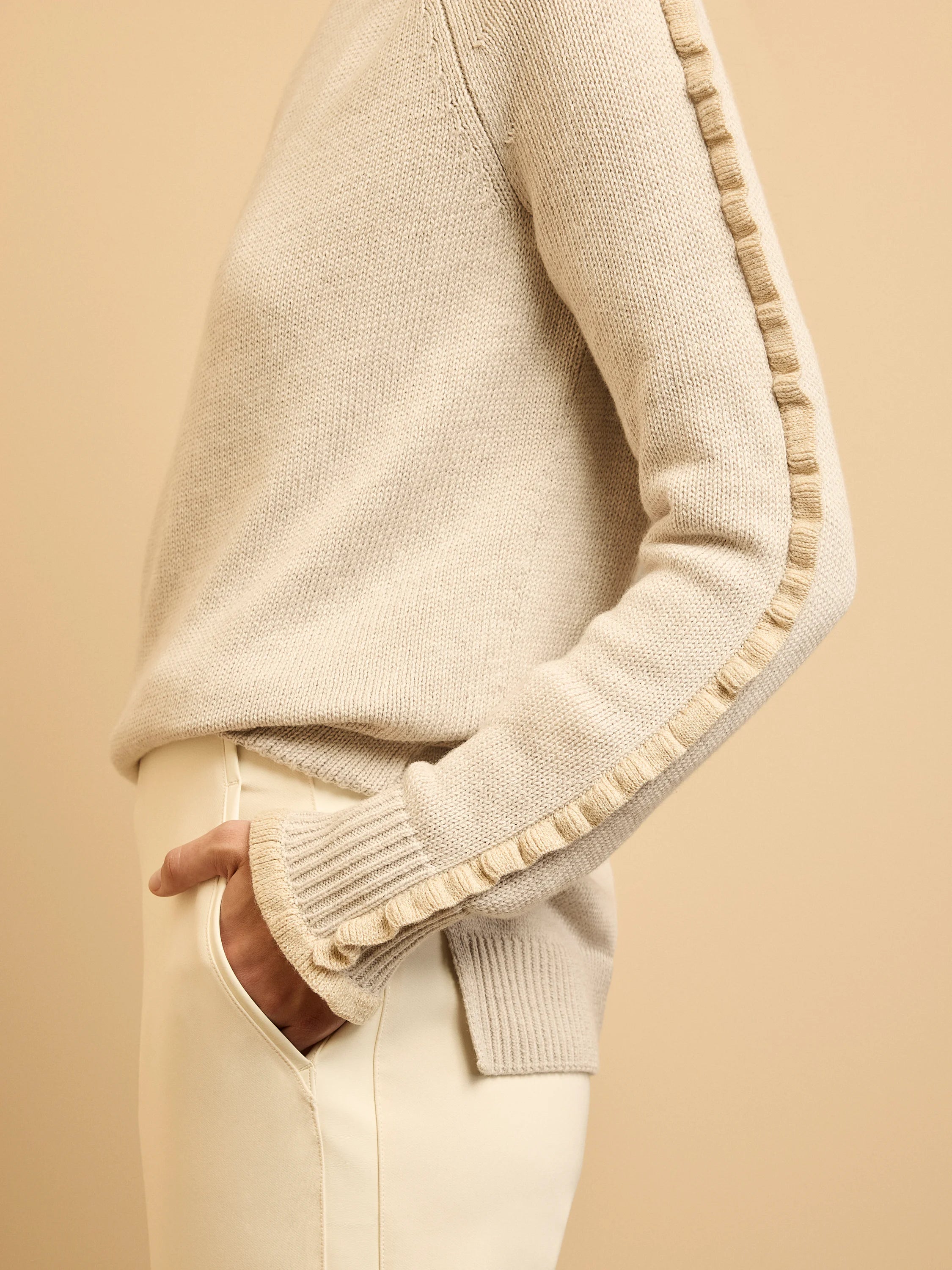 Oatmeal knit sweater with ruffles running down the sleeves and ribbed cuffs.