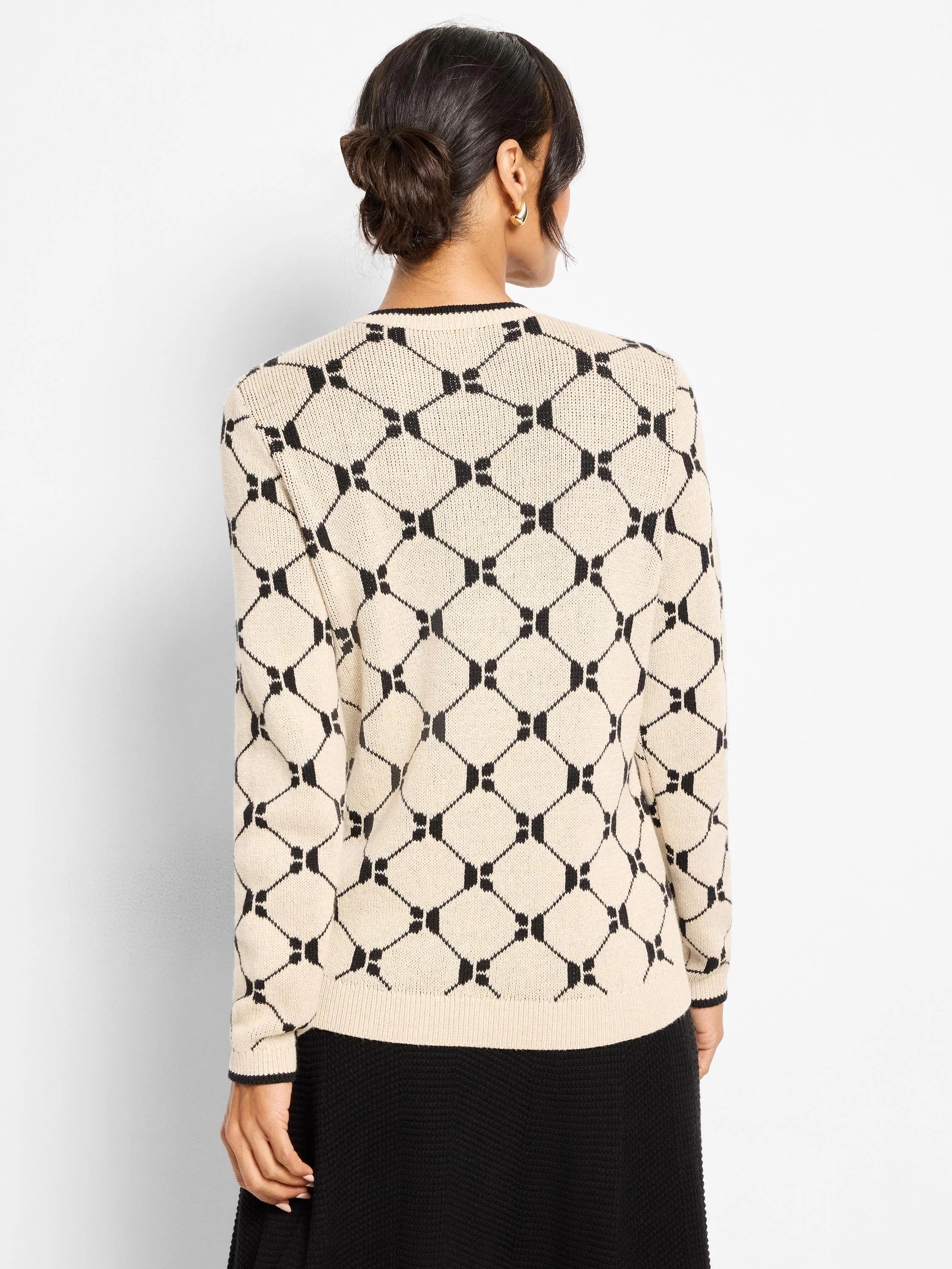 Cream sweater with black geo argyle pattern, black collar and cuff trim. Model seen from back.