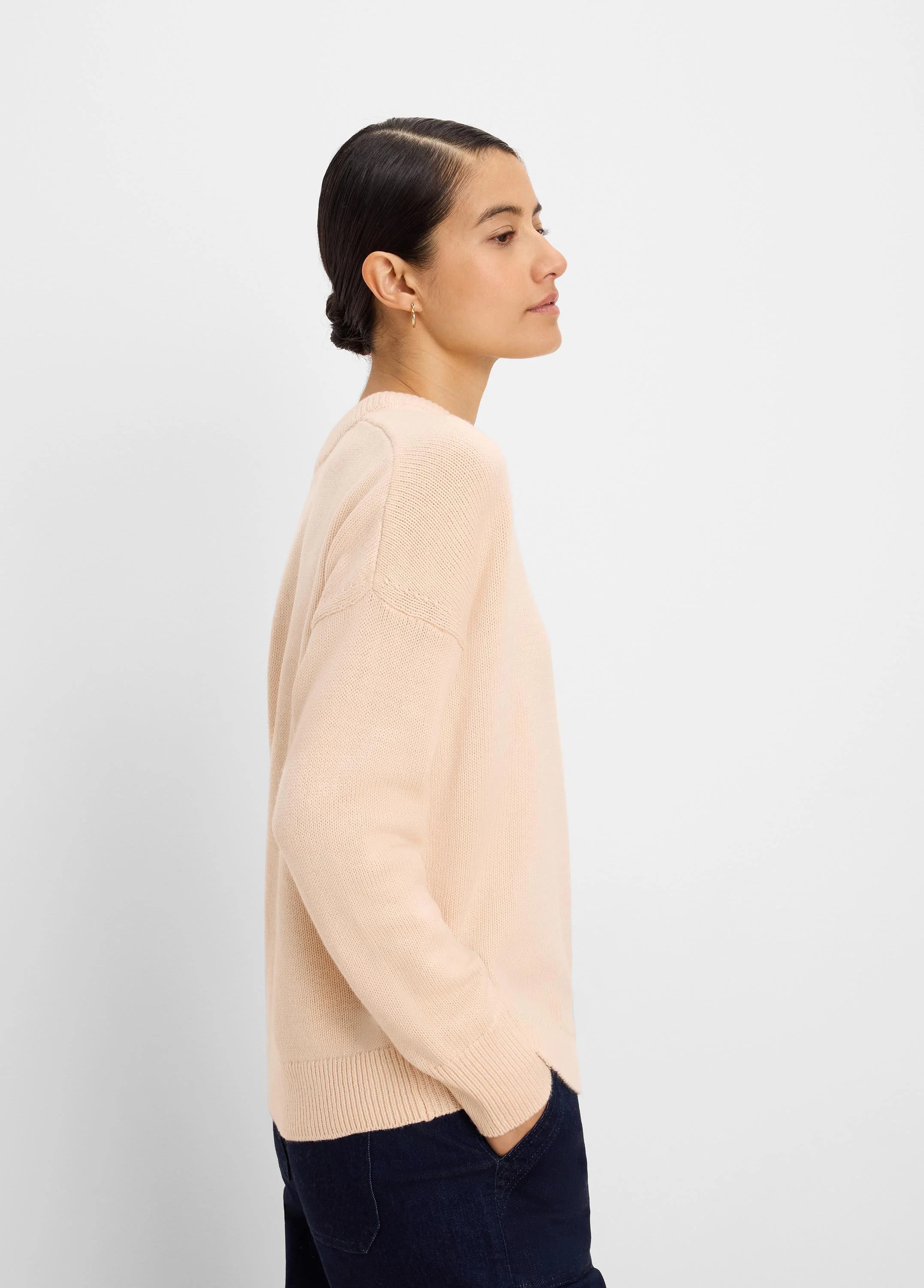 Pale nude scoop neck sweater with fine knit texture, long sleeves, and ribbed cuffs and hem.