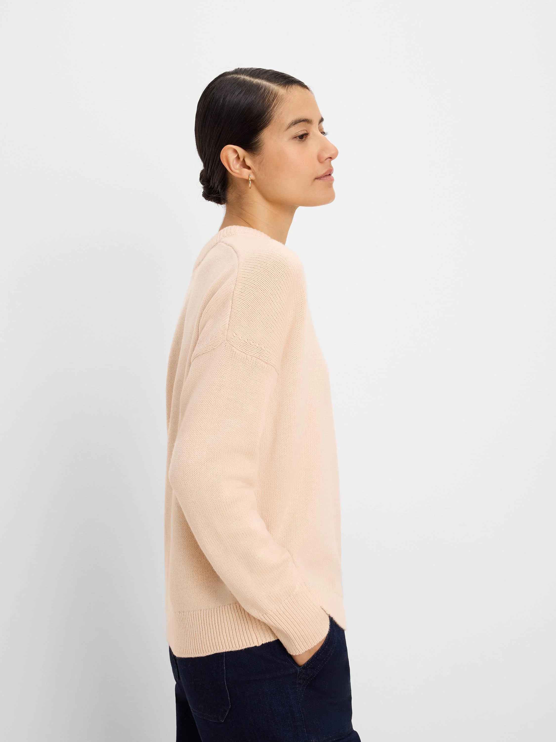 Pale nude scoop neck sweater with fine knit texture, long sleeves, and ribbed cuffs and hem.