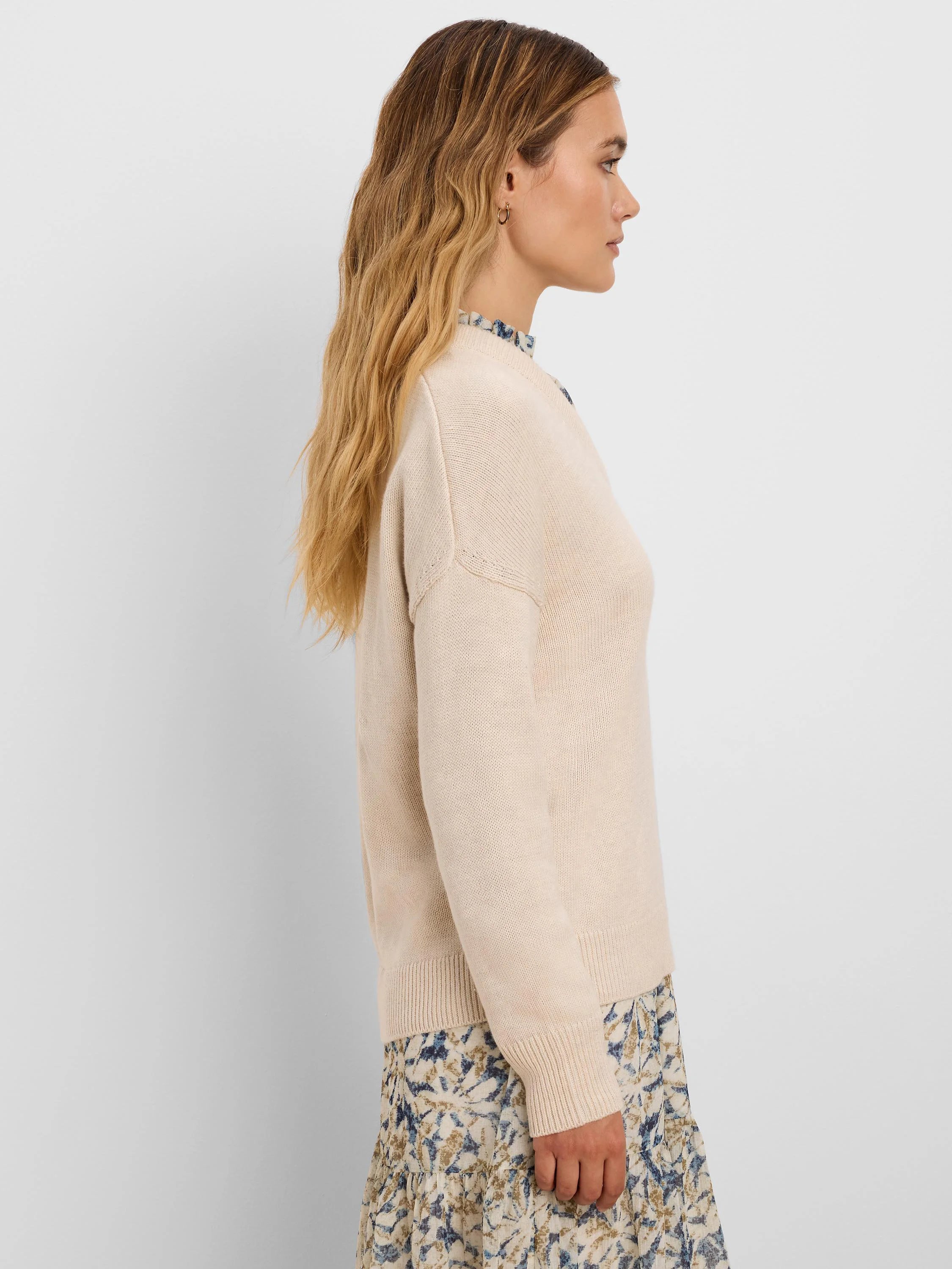 Light beige fine-knit sweater with ribbed cuffs, hem, and subtle shoulder stitching.
