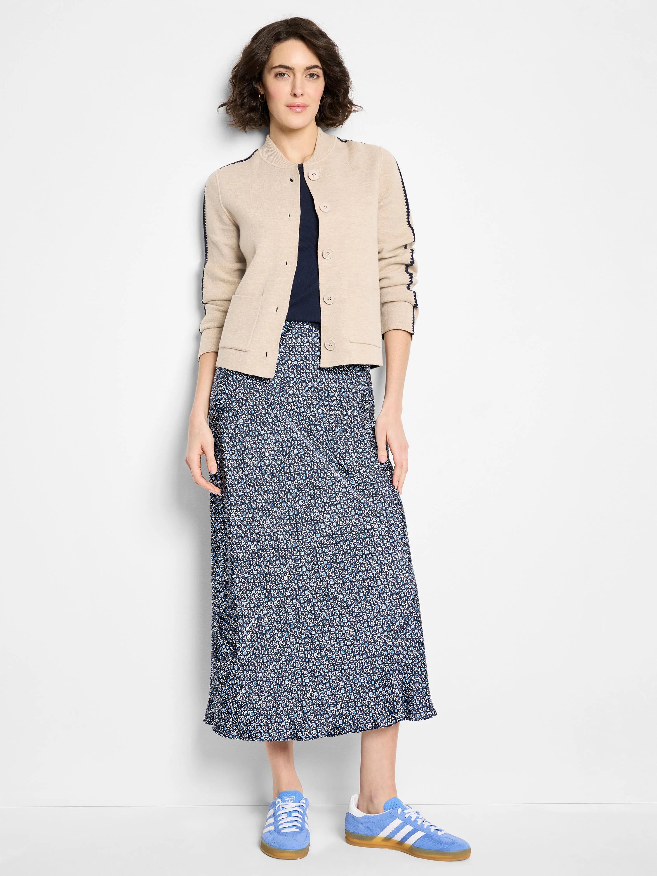 Beige knit bomber jacket with dark blue trim on collar, placket, and sleeves. Button front, two front patch pockets.