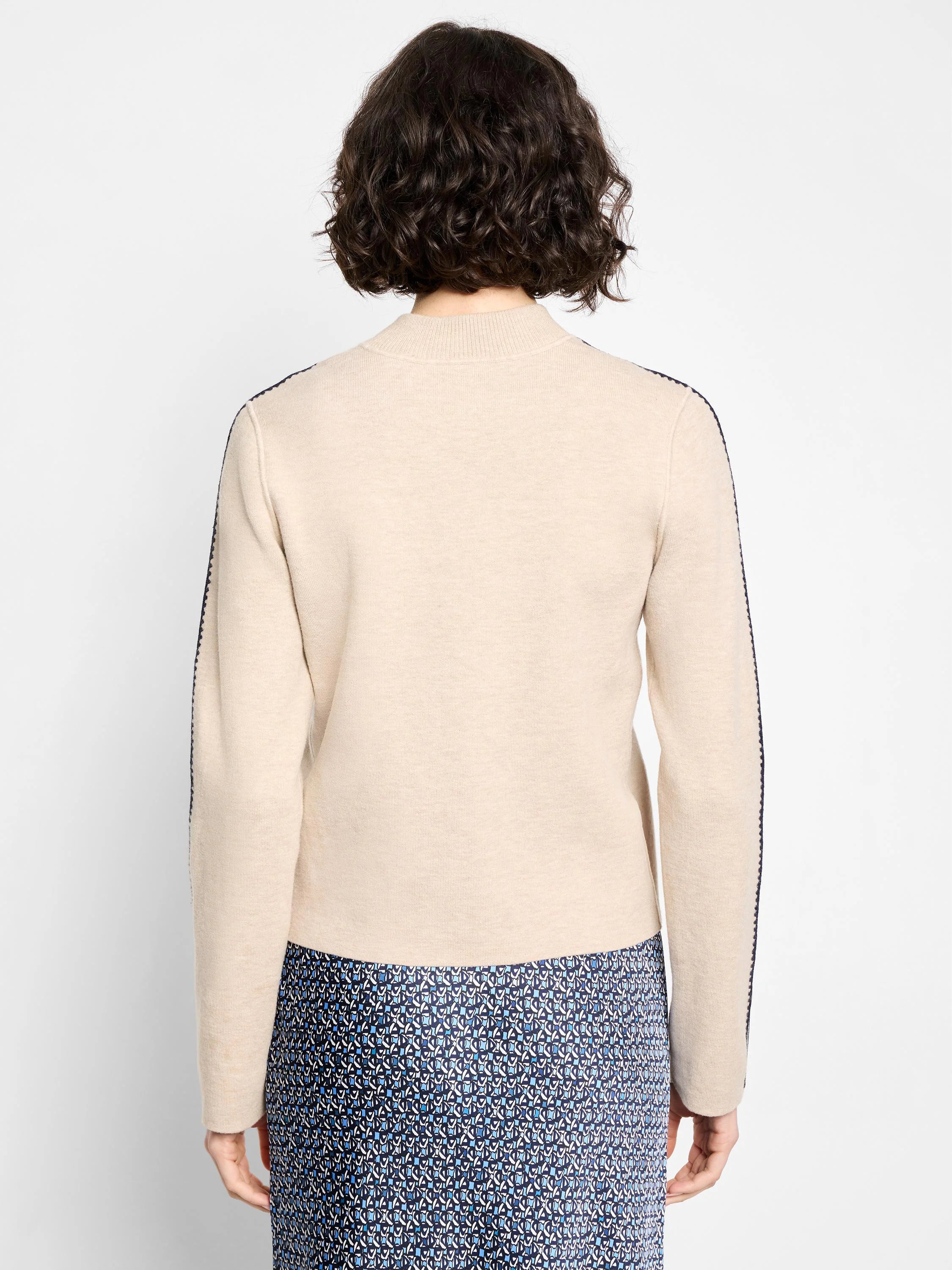 Oatmeal knit bomber jacket, back view. Dark blue piping accents along shoulders and sleeves.