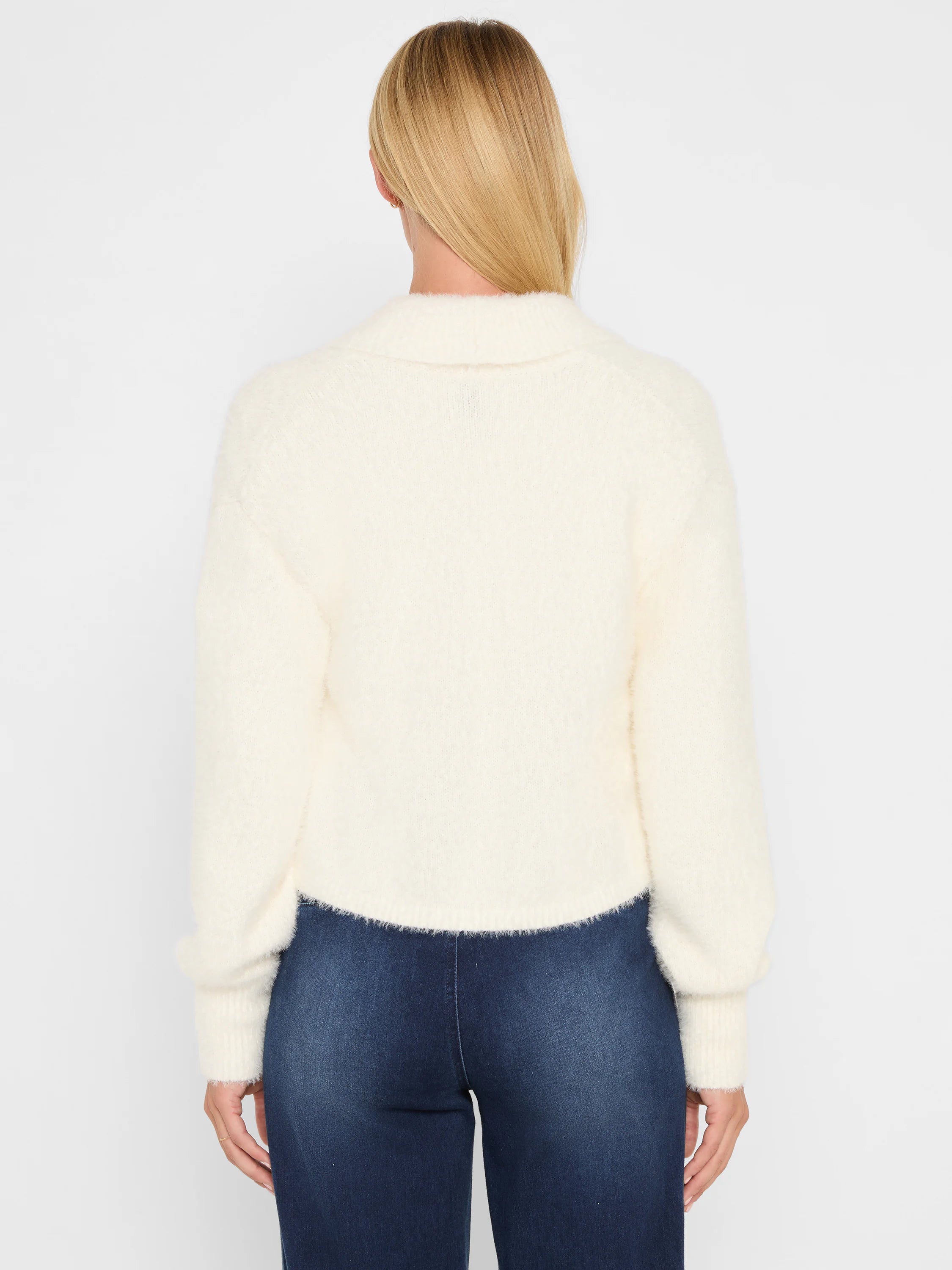 Cream fuzzy knit shrug cardigan. Cropped, with a collar and long sleeves. Back view on a model.