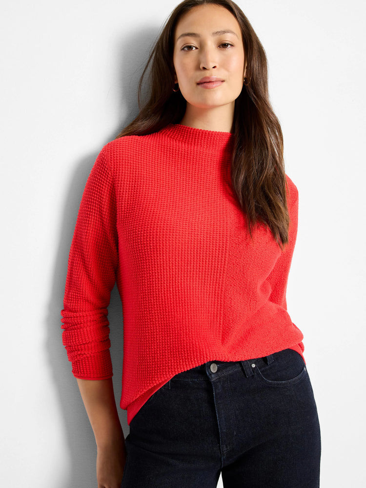 Red pixel knit sweater with a mock neck and long sleeves, shown on a model with a casual, slightly tucked fit.