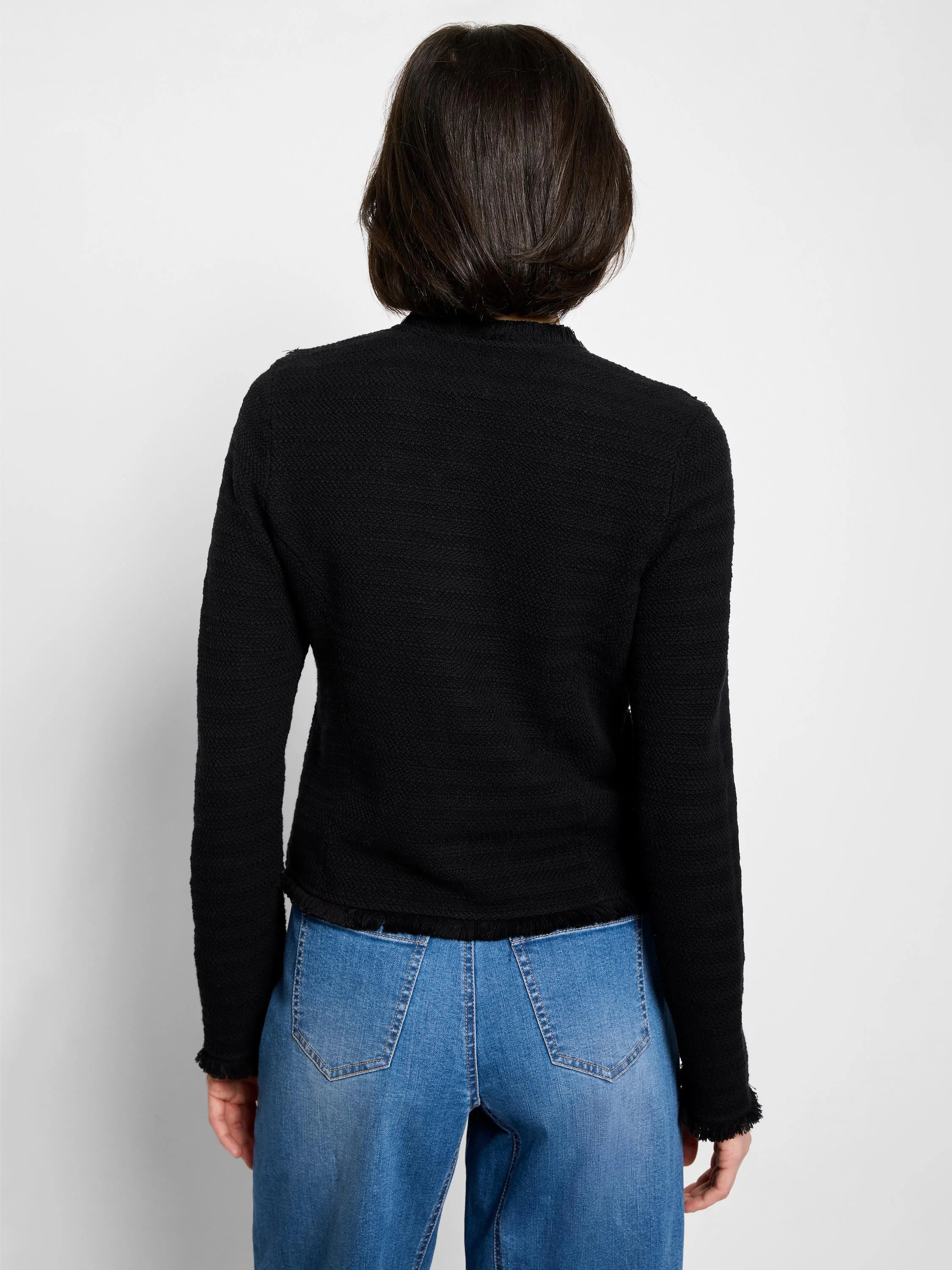 Black knit jacket, long sleeves, textured fabric, frayed hem and cuffs. Rear view.