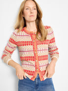 Multi-color geometric knit cardigan in red, pink, orange, and beige, with front buttons.
