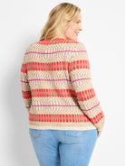 Beige, pink, and red cardigan with a geometric knit pattern featuring horizontal stripes and diamond shapes.
