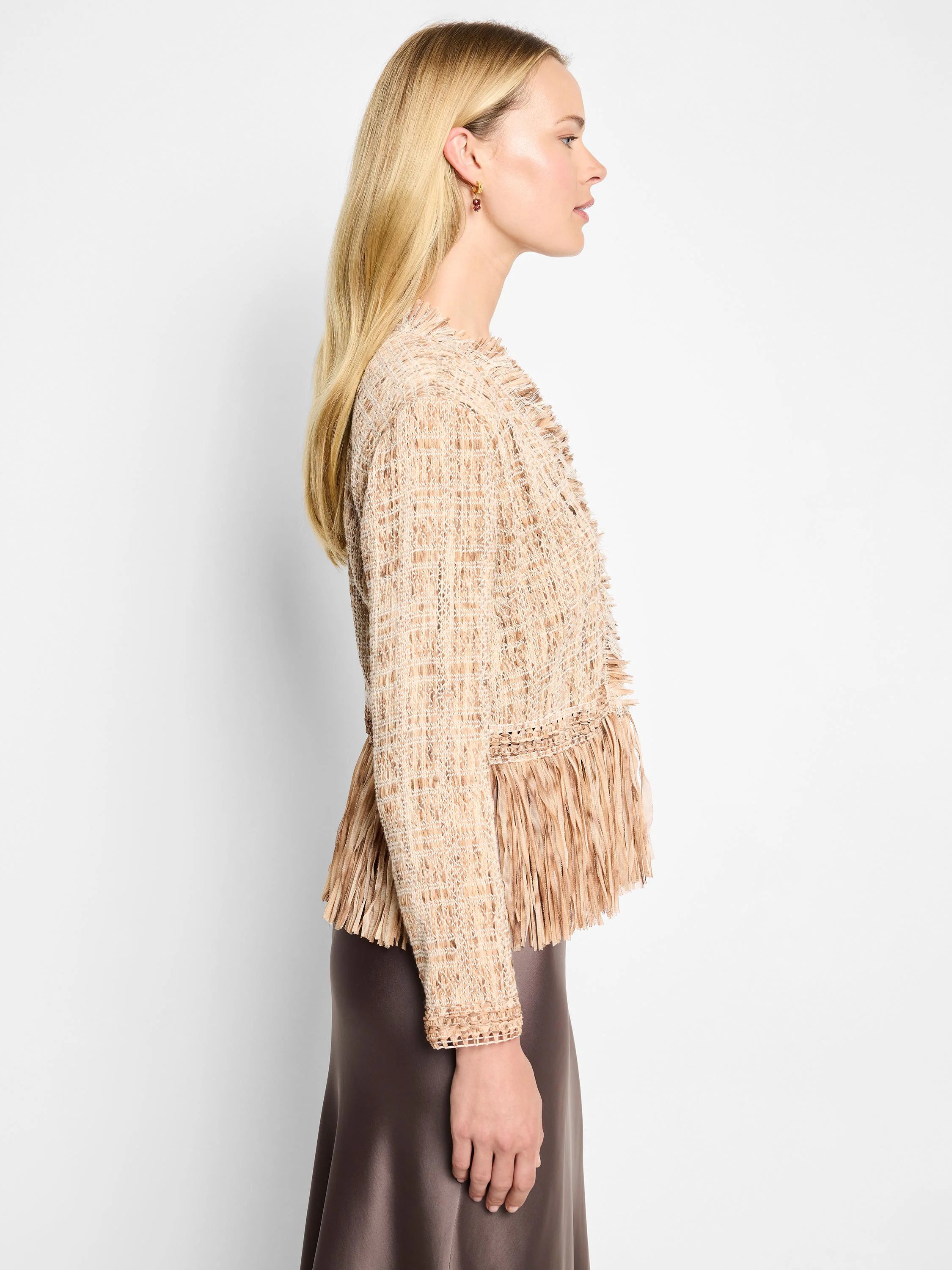 Beige knit jacket with long sleeves and a textured, fringed hem. The fringe is the same beige color as the jacket.
