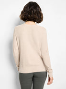 Back of a light beige waffle stitch sweater with ribbed neckline, cuffs, and hem, worn by a model.
