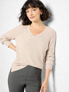 Light beige waffle stitch V-neck sweater with long sleeves and ribbed cuffs.