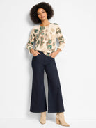 Cream sweater with abstract green and brown camo-like pattern, scattered with subtle sequins. Ribbed cuffs.