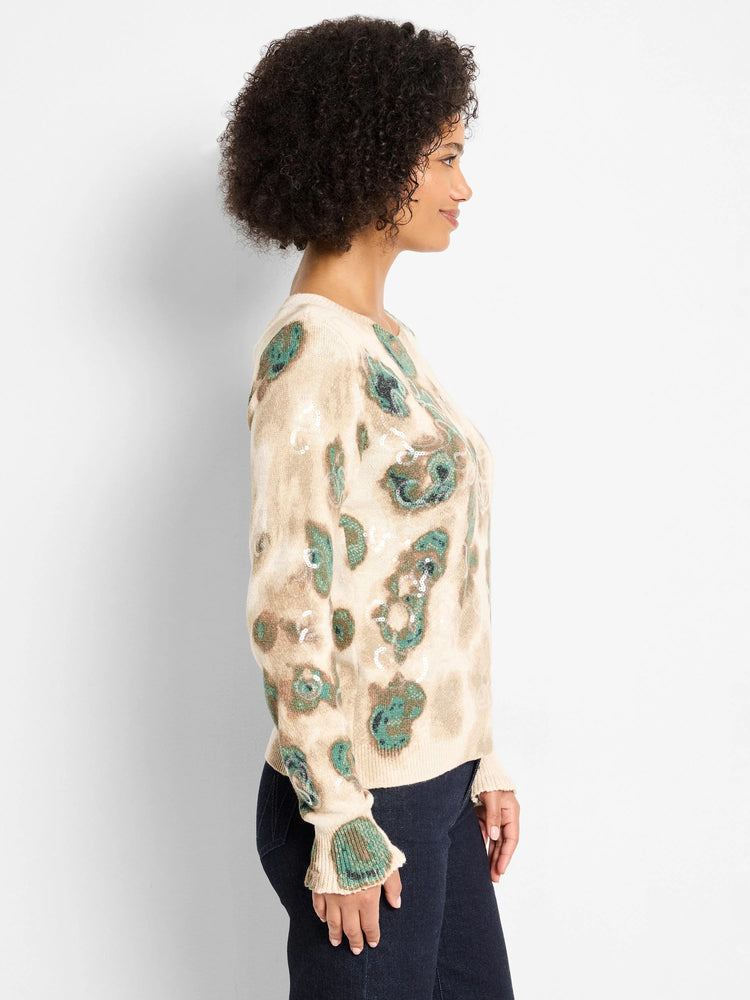 Cream sweater with abstract green/brown camo pattern, scattered sequins, and ribbed, slightly flared cuffs.