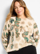 Beige sweater with green and brown abstract camouflage pattern, accented with scattered clear sequins.
