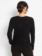 Black, long-sleeved waffle knit sweater with scattered silver shimmery specks and ribbed cuffs/hem. Model's back.