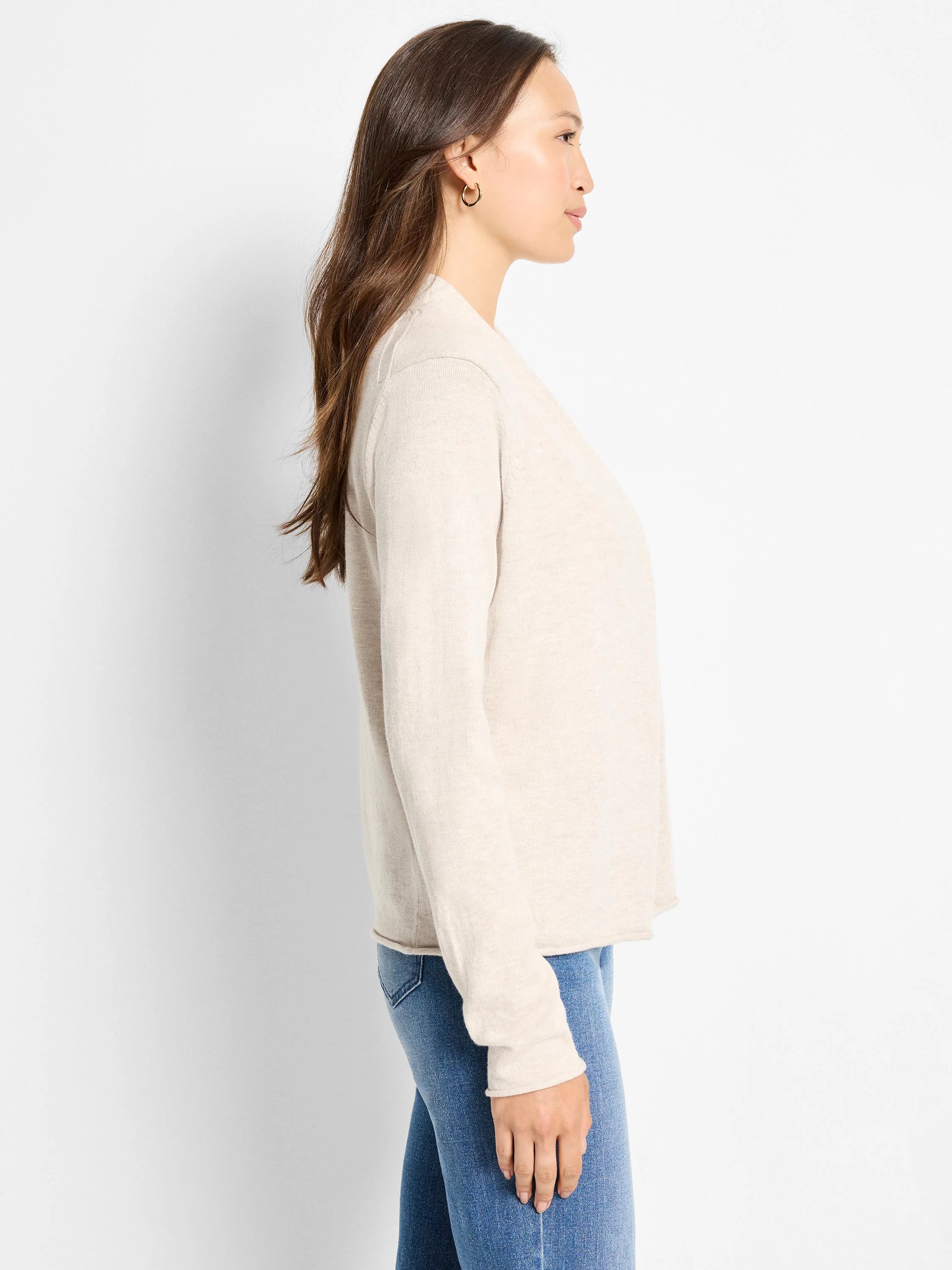 Light beige, fine-knit, open-front cardigan with long sleeves, shown on a woman from the side.