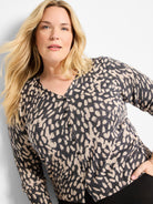 V-neck button-front sweater with an irregular beige and charcoal grey "wild dot" pattern and dark buttons.